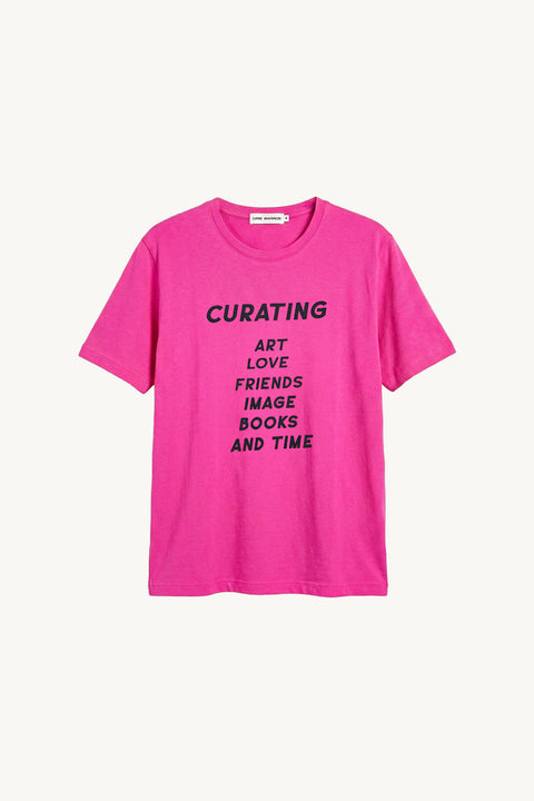 Camiseta rosa da parceria cris barros e act arte, mostrando a parte da frente, escrito curating, art, love, friends, image, books and time